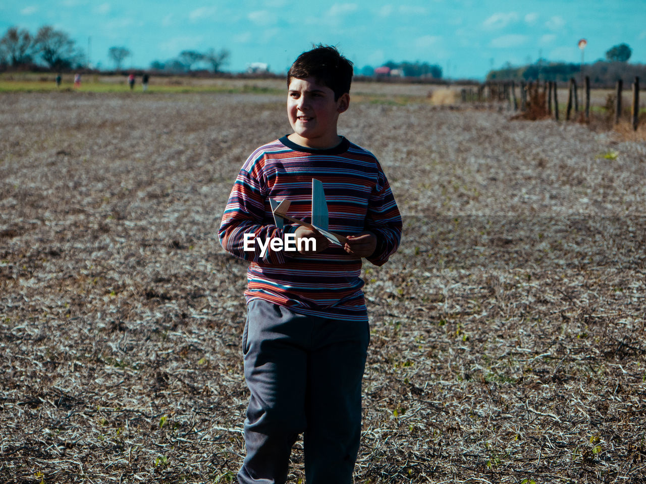 Boy with toy airplane walking on land