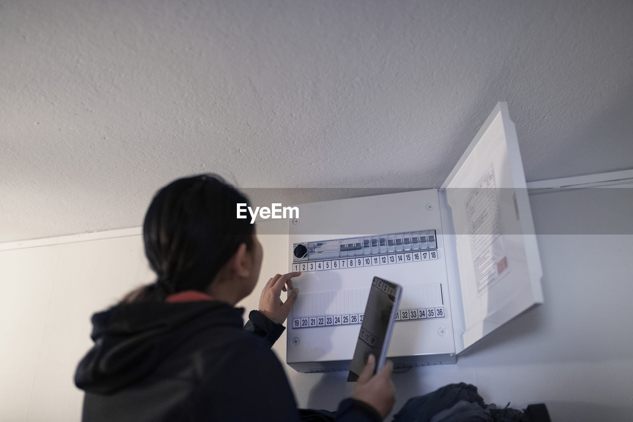 Woman checking electric fuse box