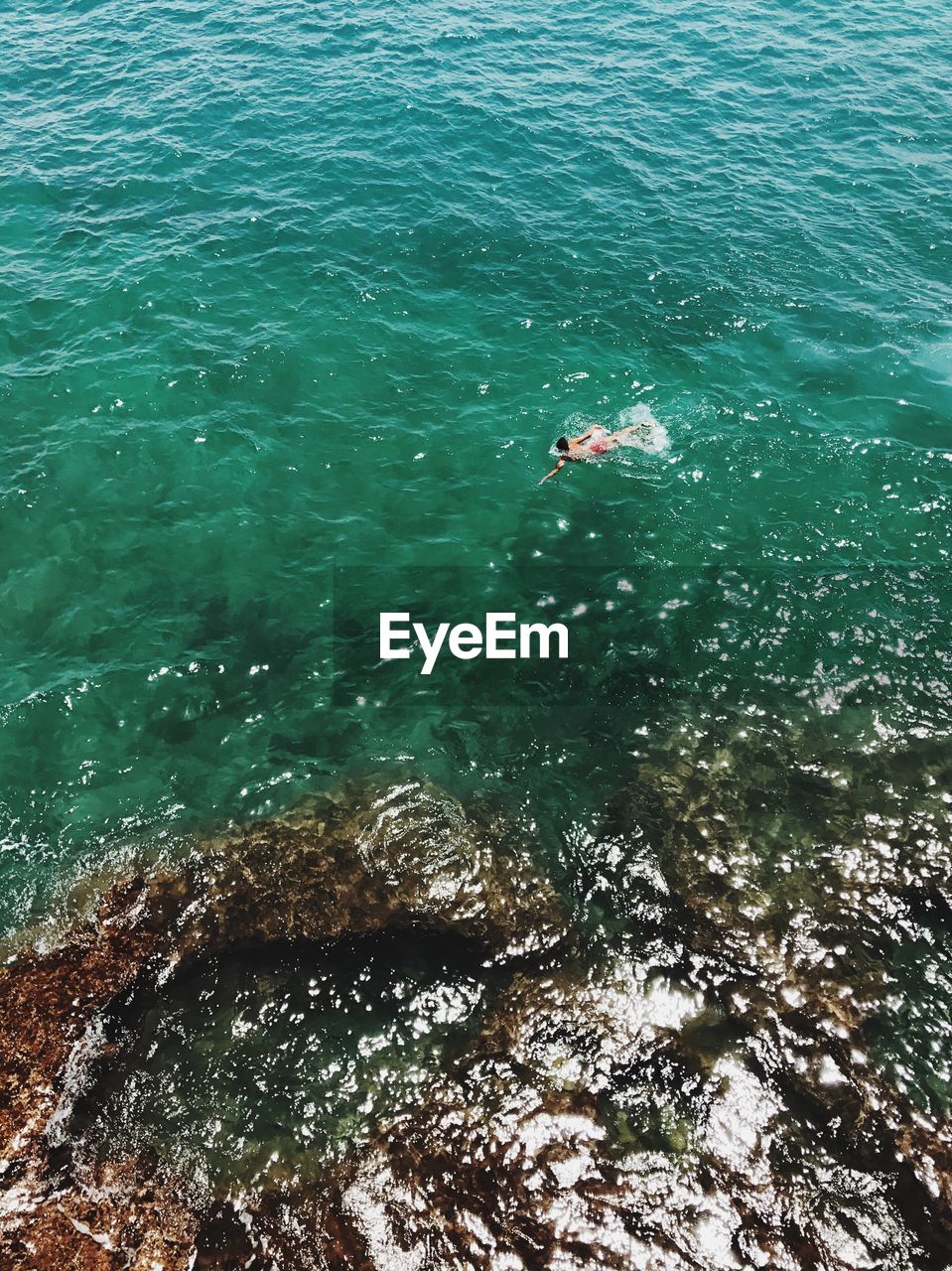 High angle view of man swimming in sea on sunny day