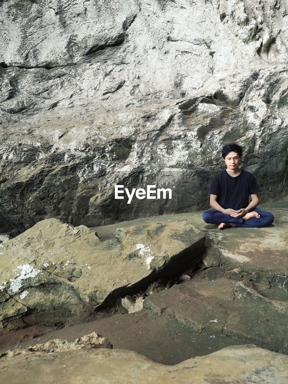 Full length of man practicing yoga on rock