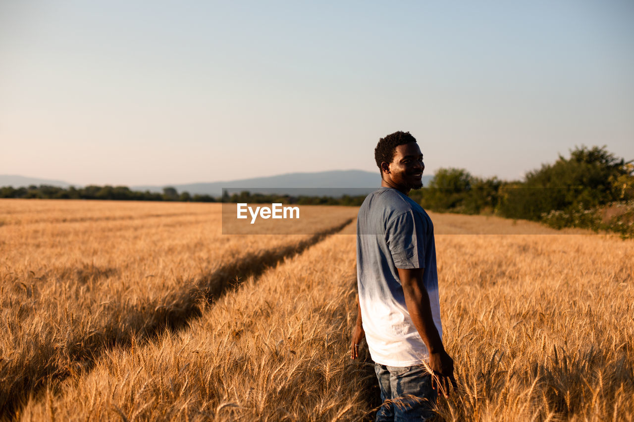 Smiling young man standing on crop field