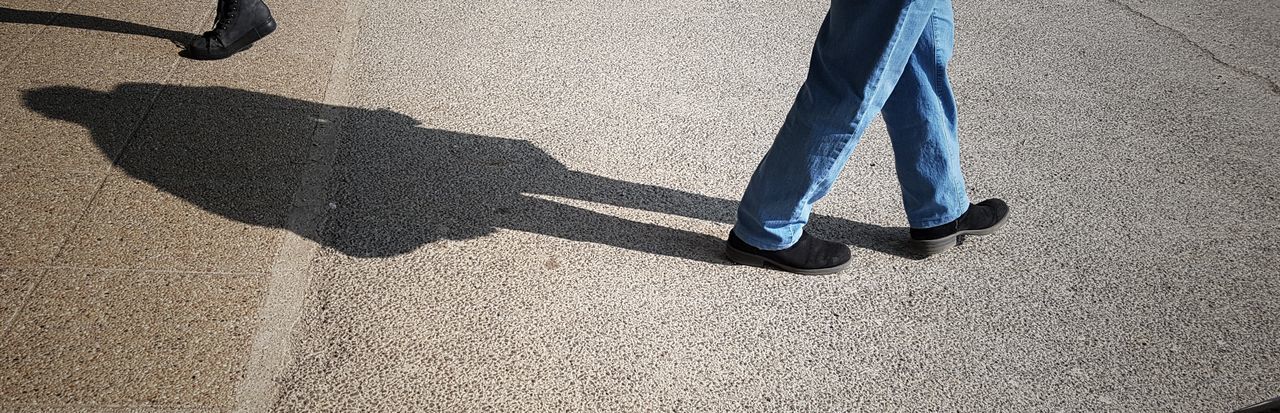 LOW SECTION OF MAN ON SHADOW OF PERSON