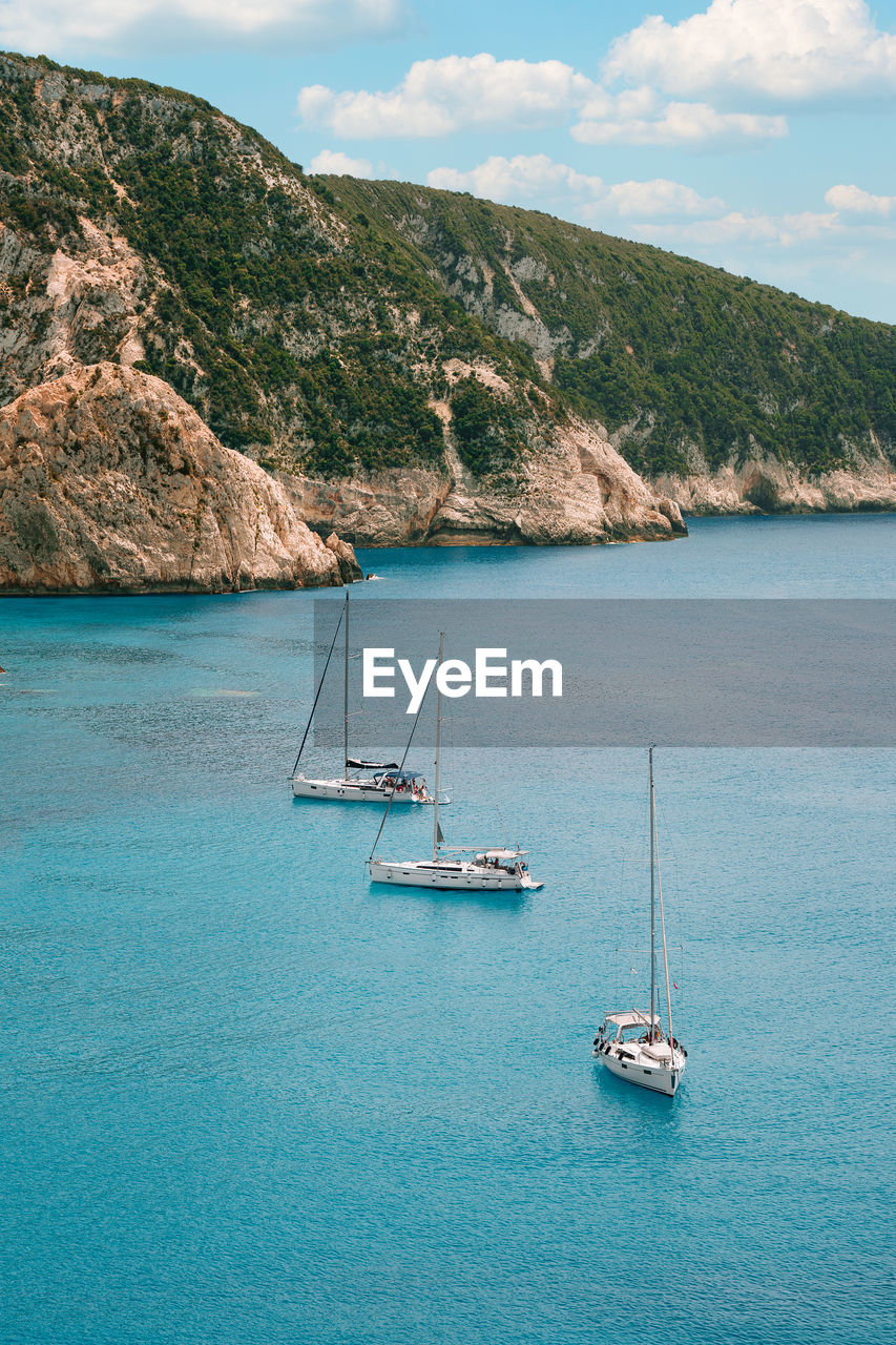 Sailboat sailing on sea against mountain