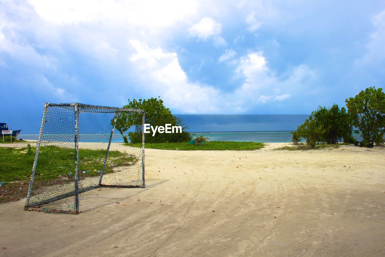 Goal post at sandy beach against sky