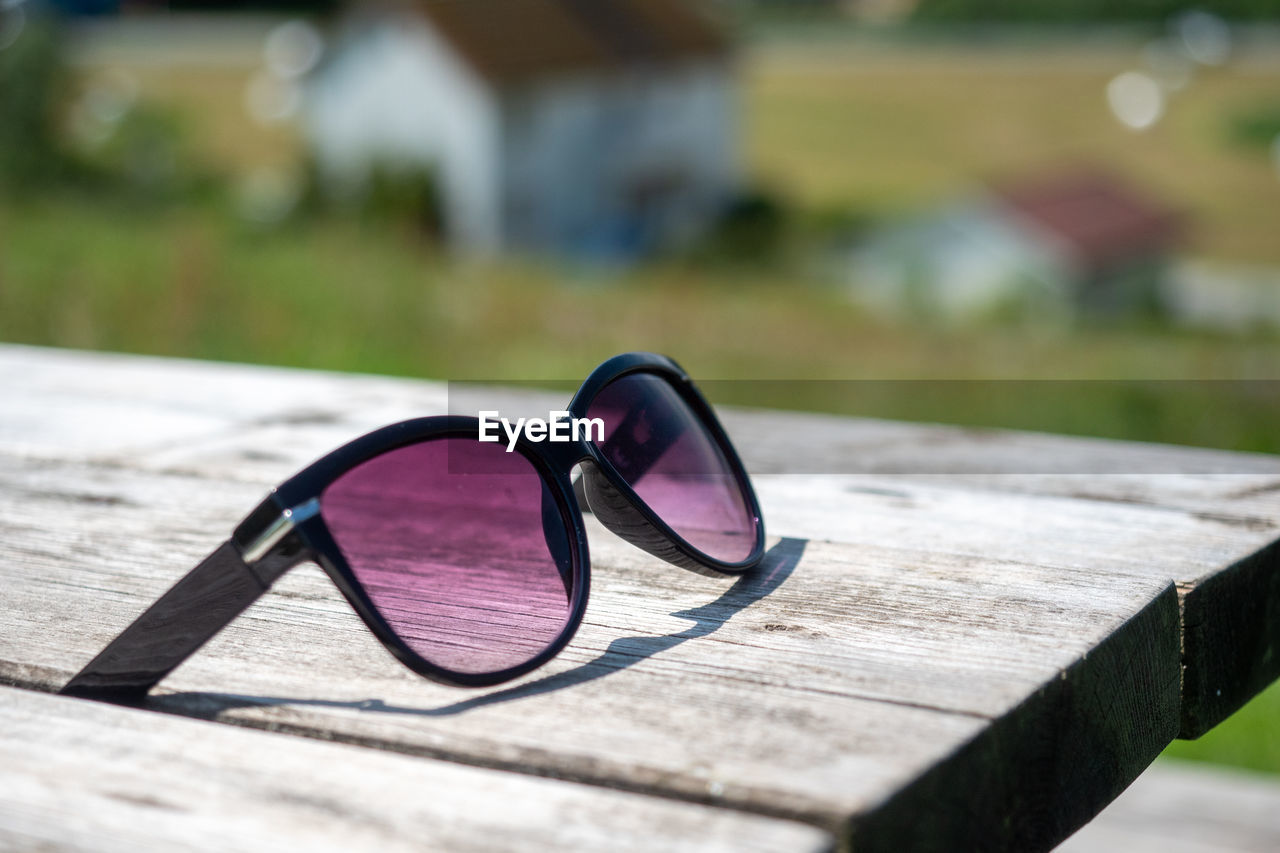 CLOSE-UP OF SUNGLASSES ON TABLE OUTDOORS