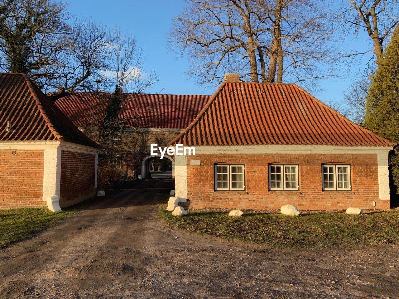 House amidst bare trees and buildings against sky