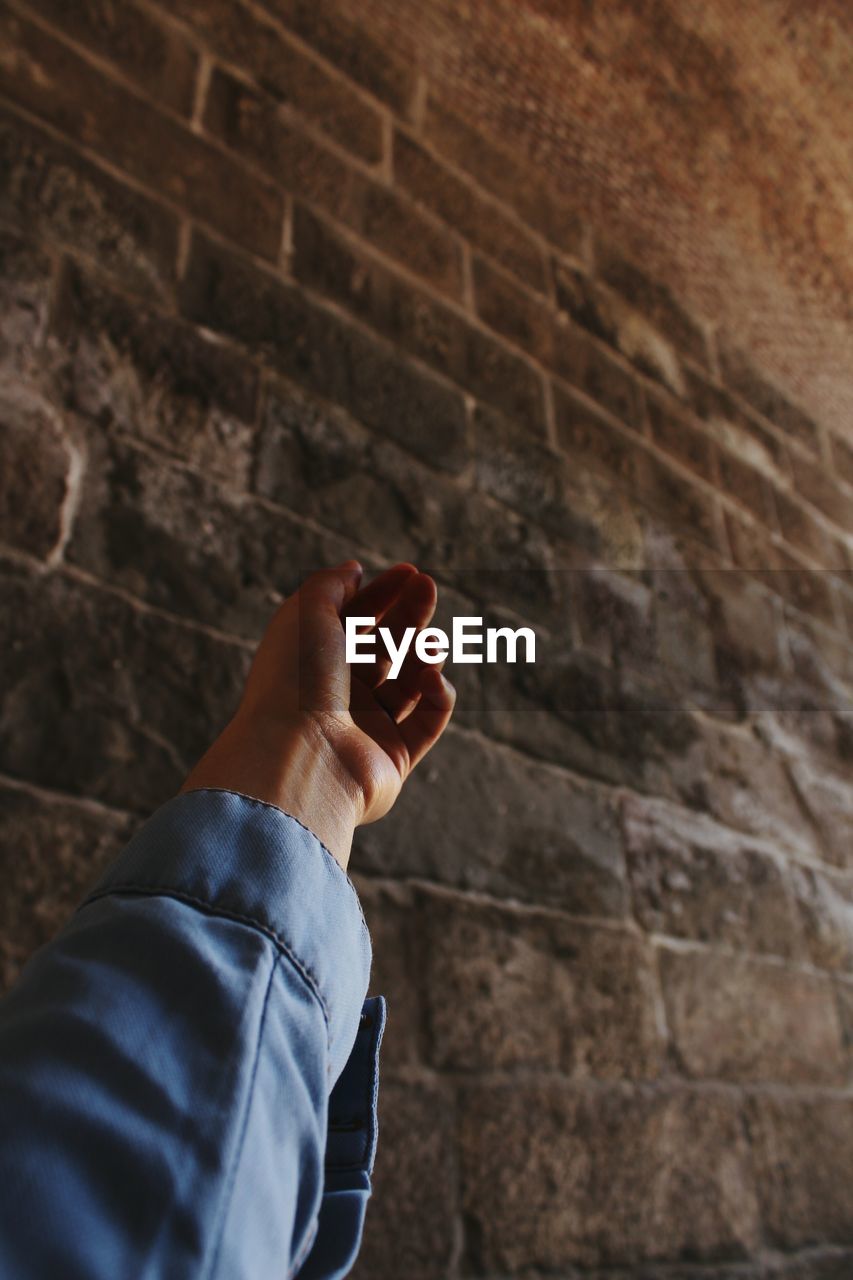 CROPPED IMAGE OF PERSON HAND HOLDING WALL