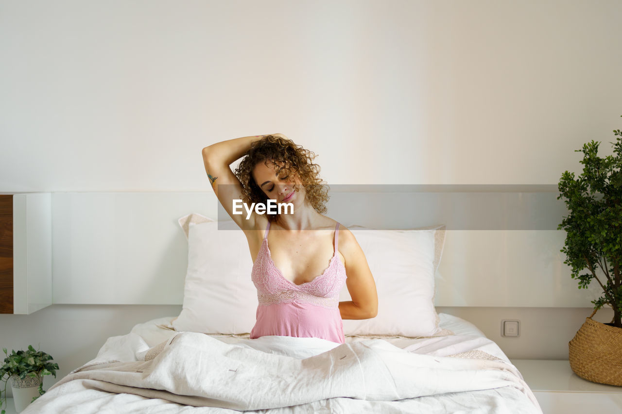 portrait of beautiful young woman sitting on bed at home