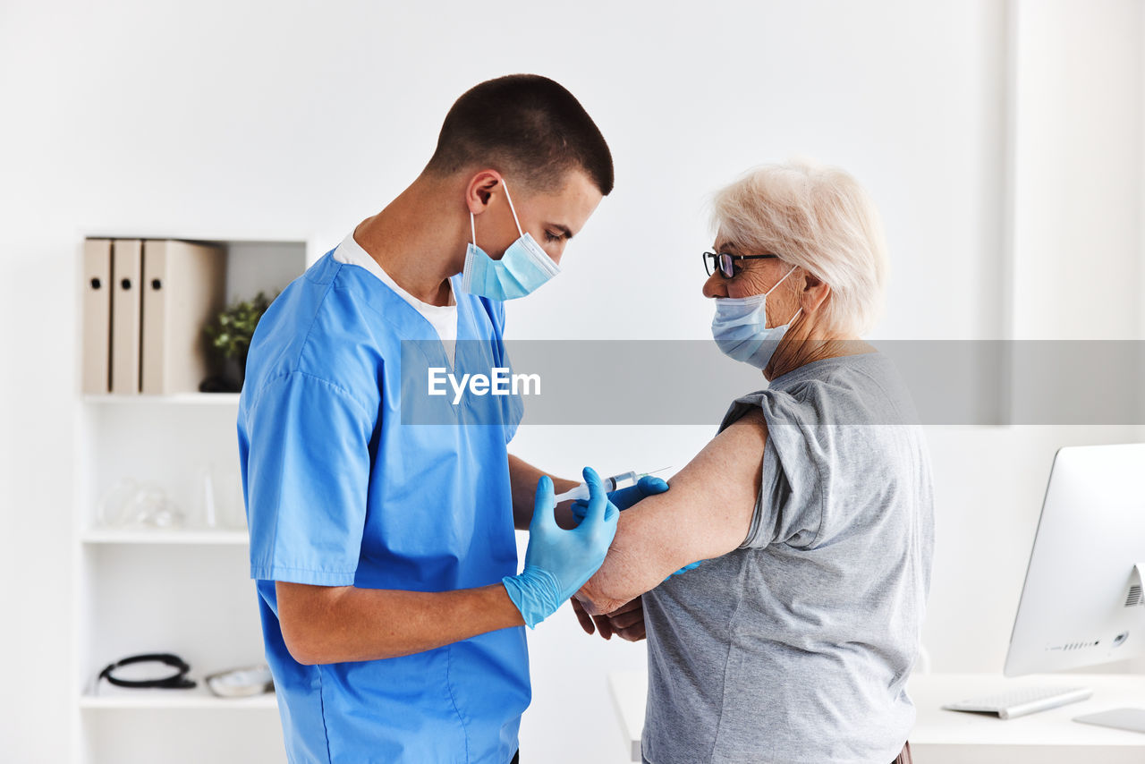 Nurse wearing mask vaccinating patient at clinic