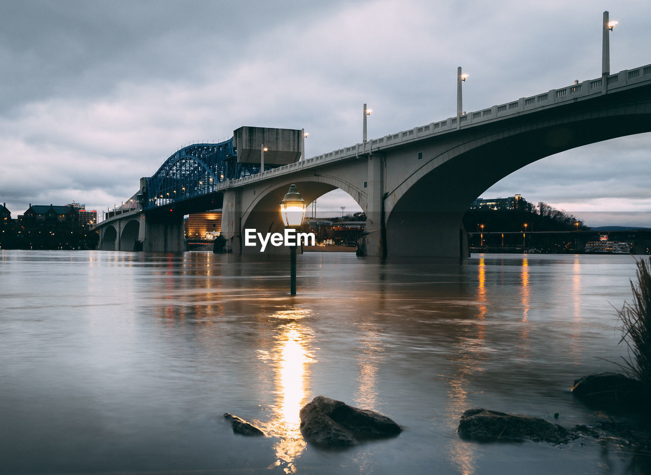 Bridge over river against sky at sunset