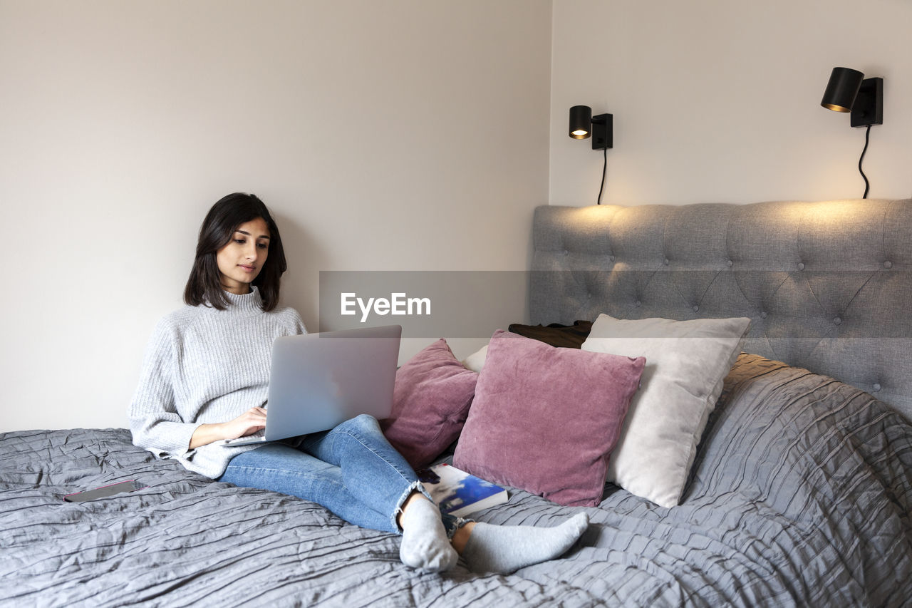 Young woman using laptop on bed