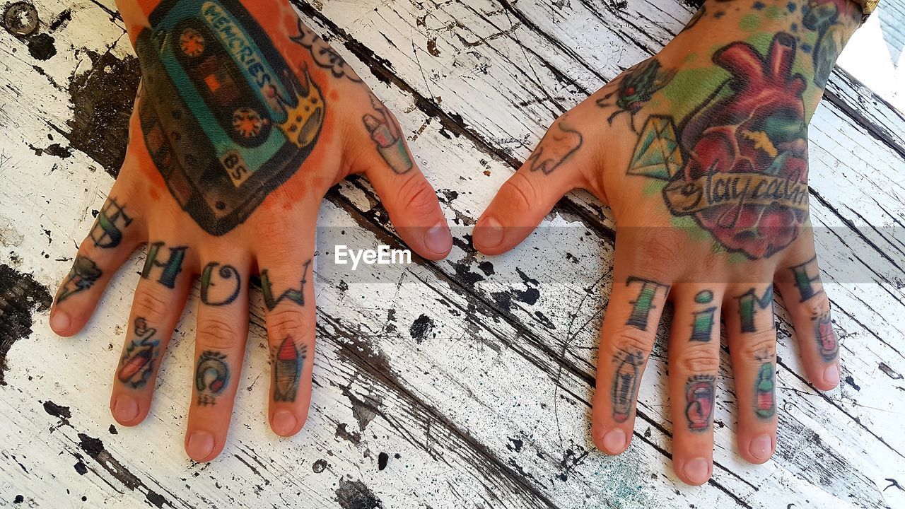 Close-up of hands with tattoo on table