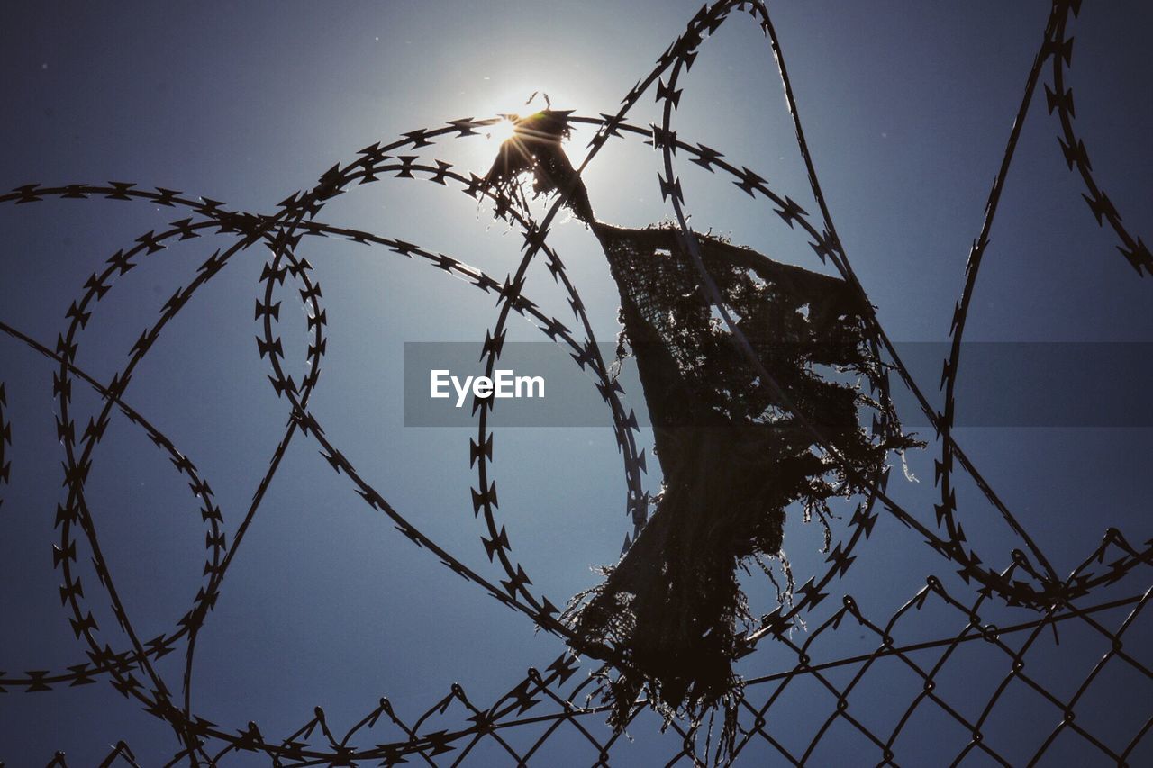 Low angle view of barbed wire fence against clear sky