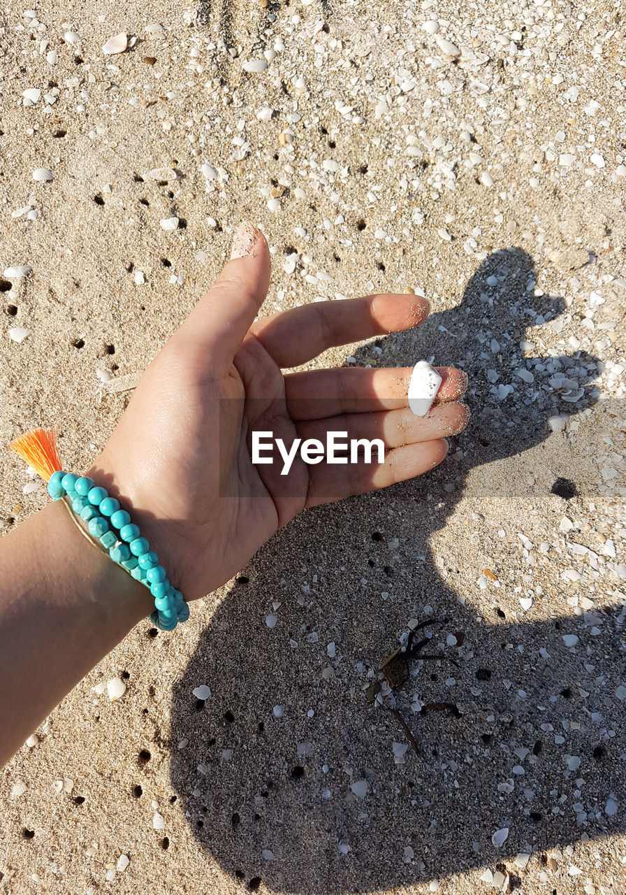 HIGH ANGLE VIEW OF HUMAN HAND HOLDING SAND