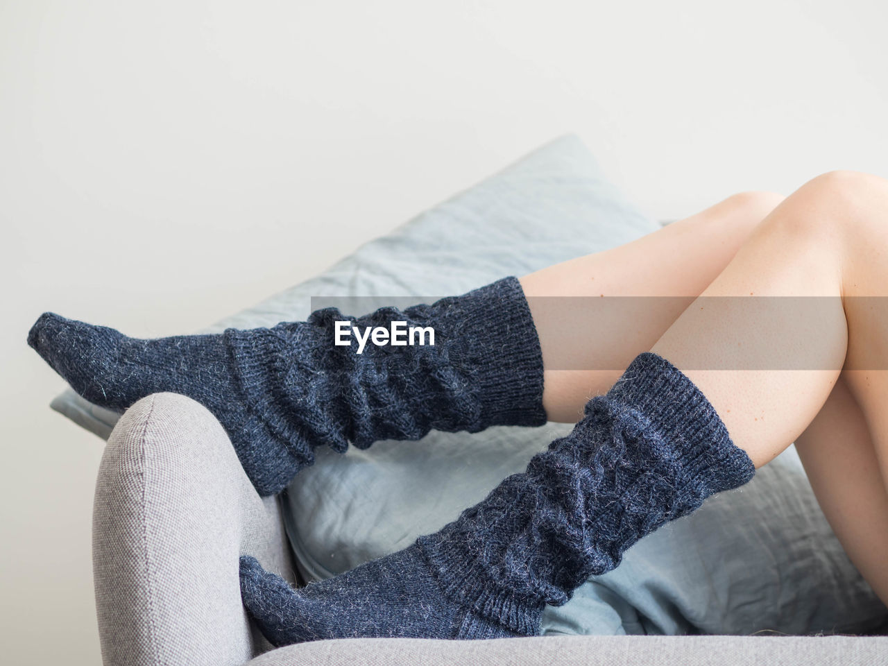 Low section of woman in socks sitting on sofa at home