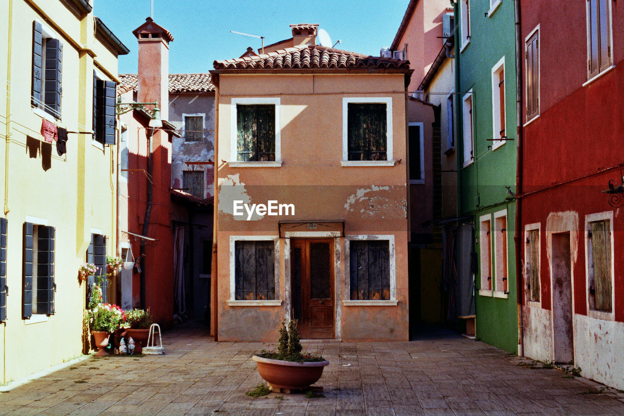 ALLEY AMIDST HOUSES AGAINST BUILDINGS