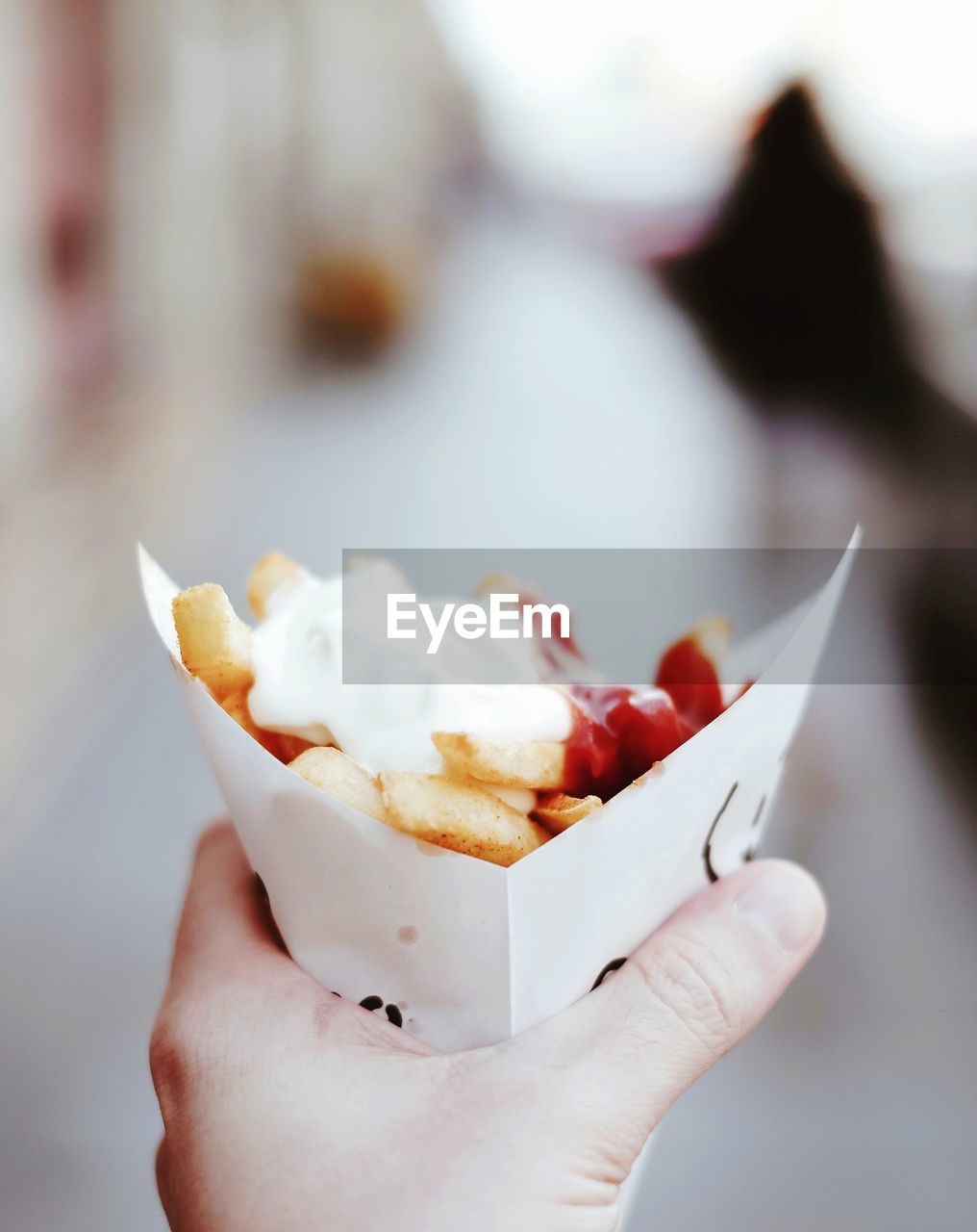 Cropped hand of person holding potato chips cone outdoors