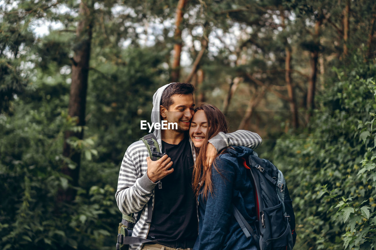 Young couple standing against trees