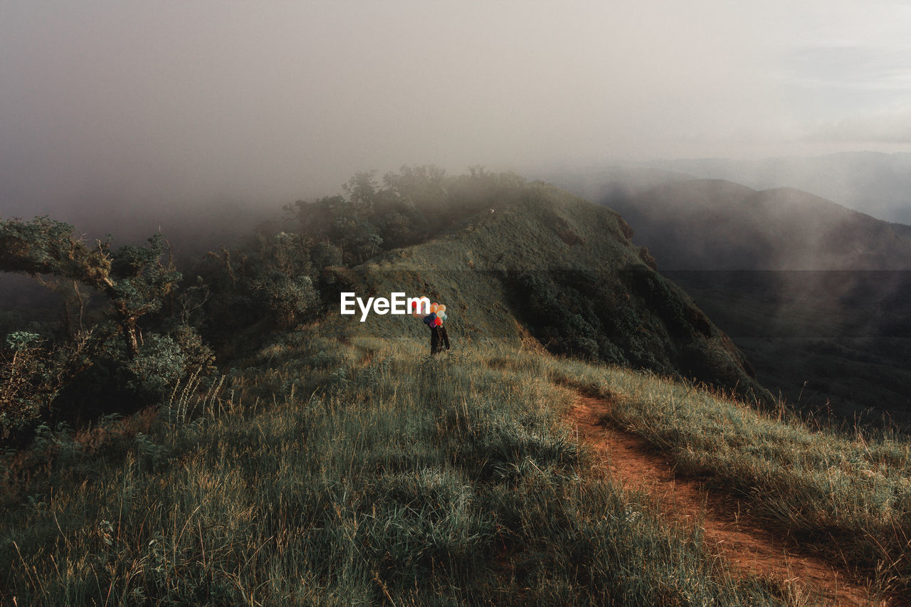 PERSON ON MOUNTAIN AGAINST SKY