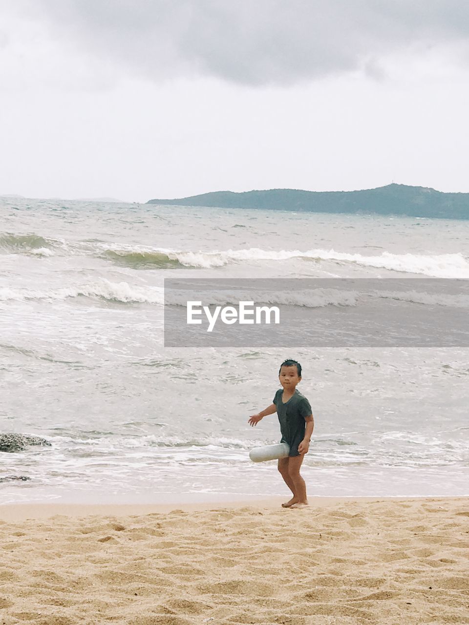 MAN STANDING ON BEACH AGAINST SKY