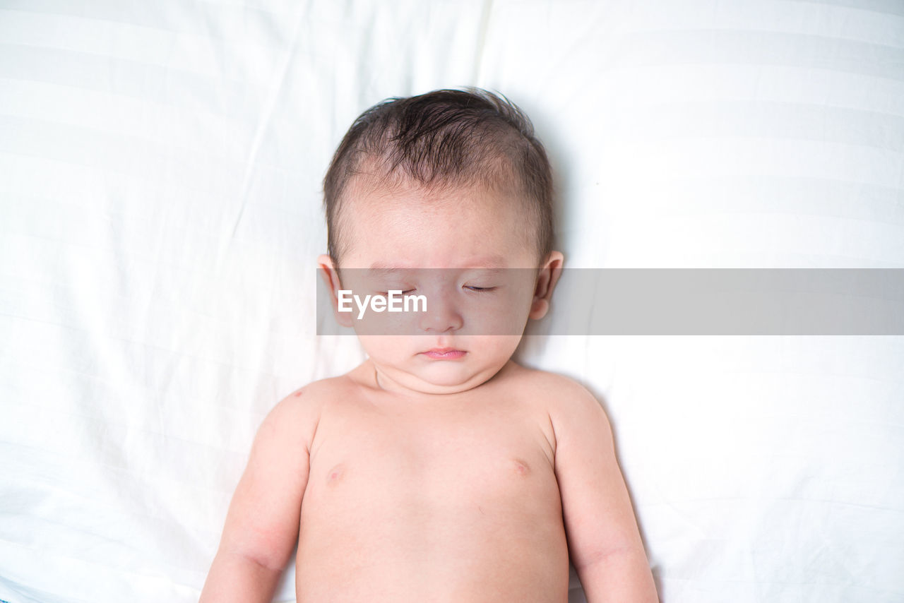 High angle view of shirtless baby sleeping on bed