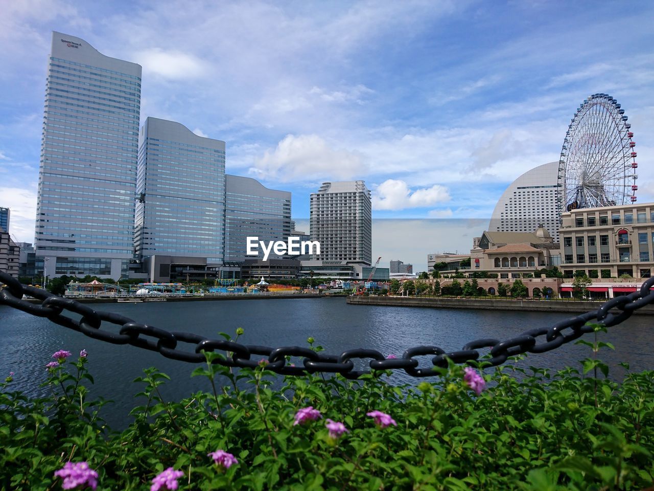 View of buildings by river against cloudy sky