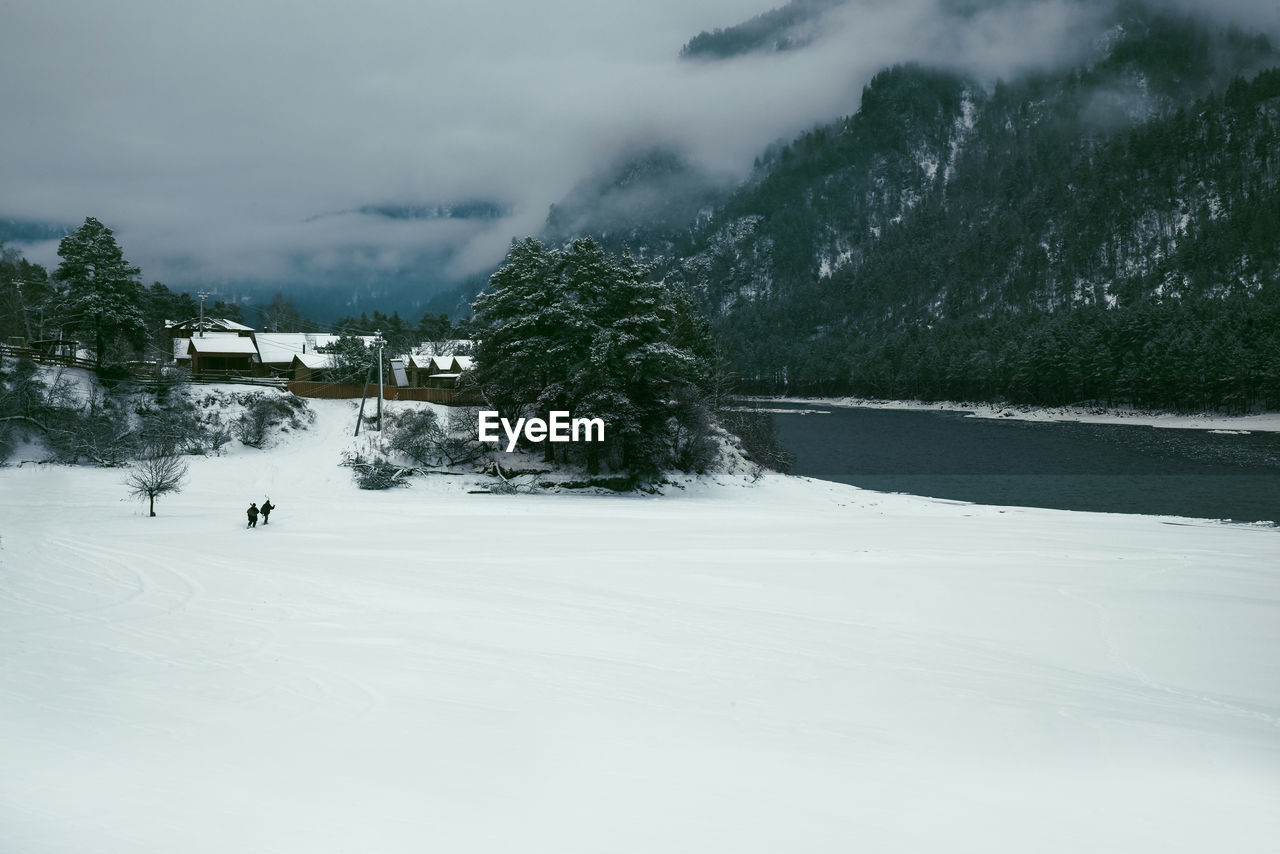 Winter landscape with a village in the mountains on the bank of a mountain river