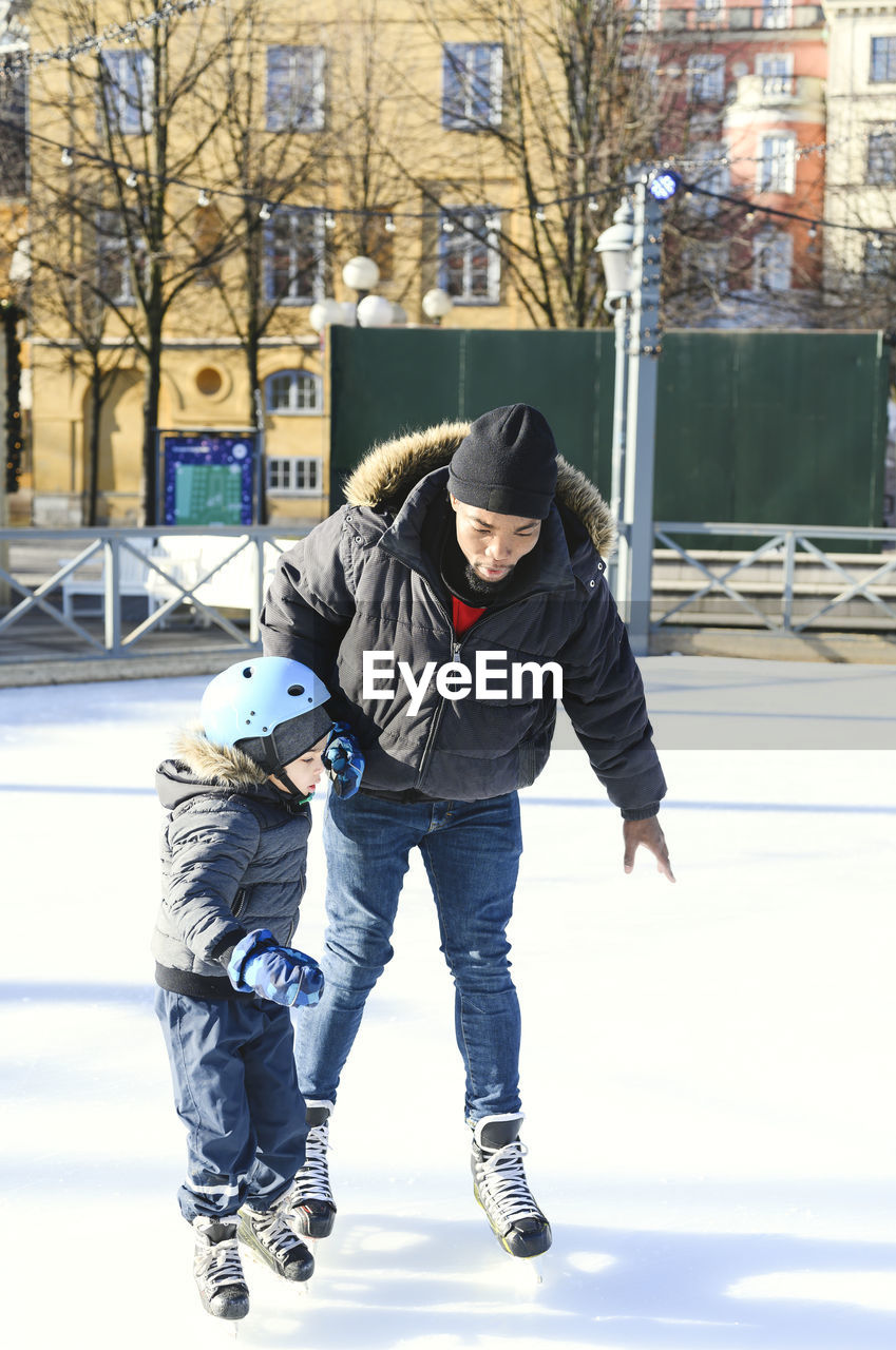 Father teaching son ice-skating