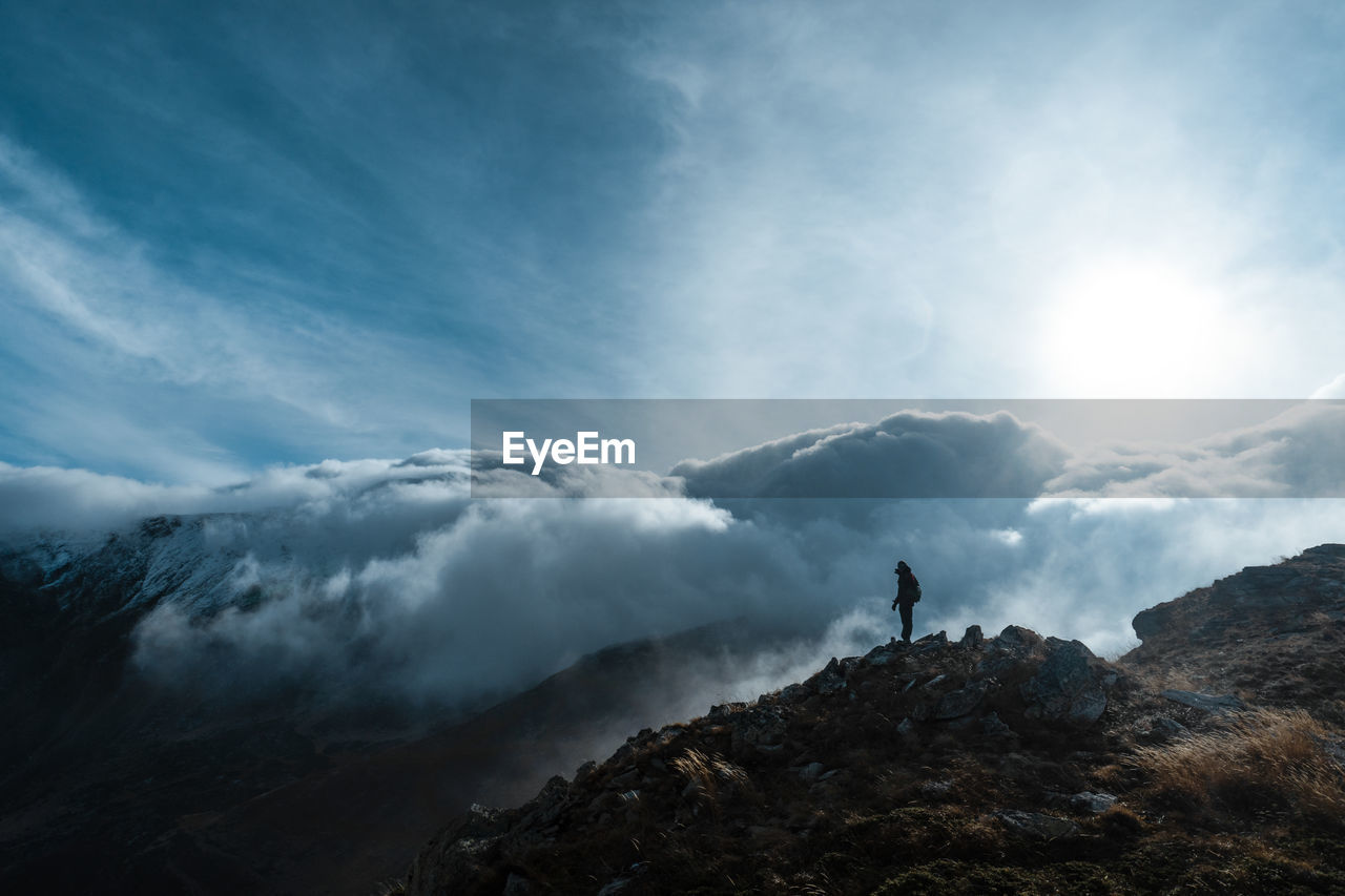 Man standing on mountain against cloudy sky