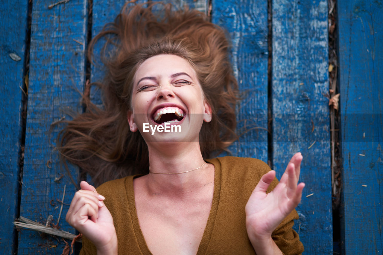 Smiling woman against blue wooden wall