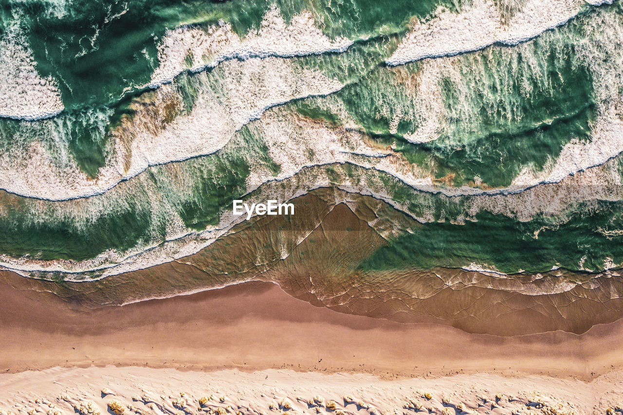 Aerial view of waves in sea during sunny day