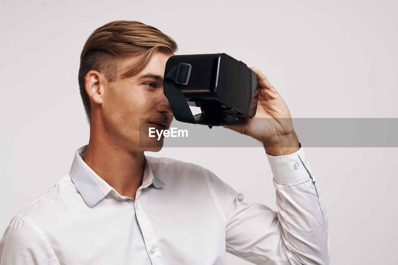 portrait of young man photographing with camera against white background