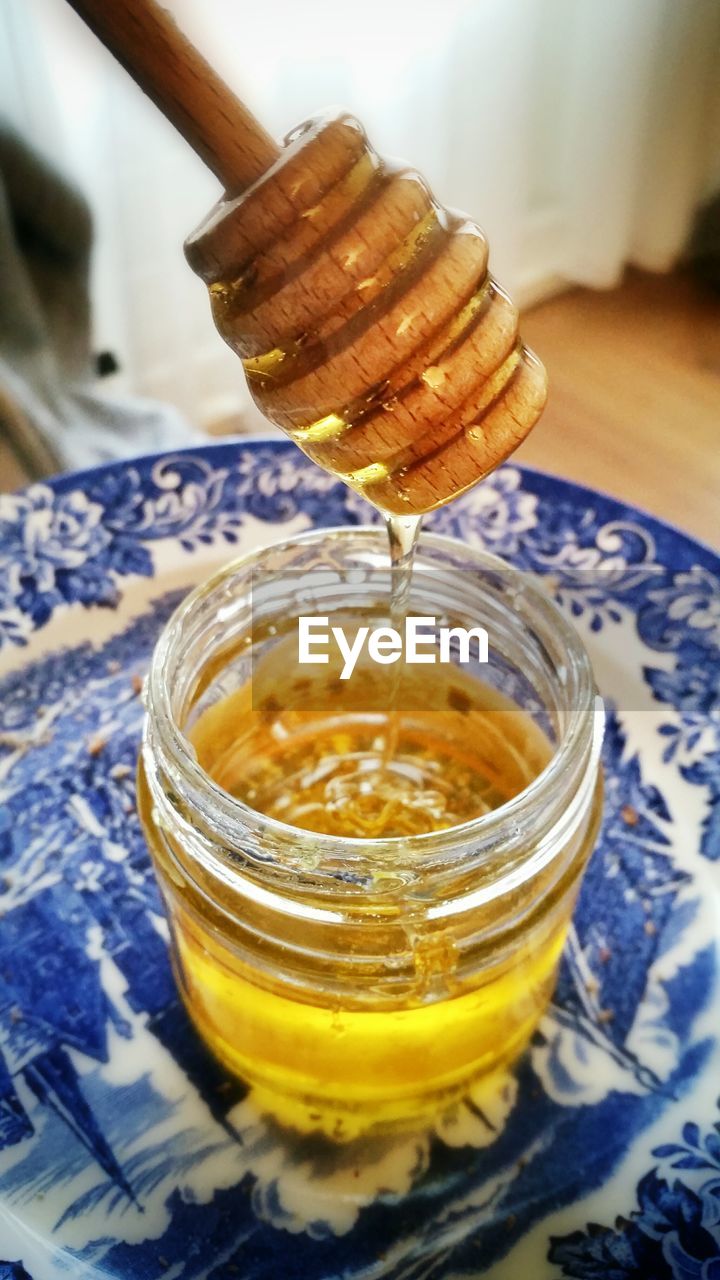 Honey dripping off from dipper into jar