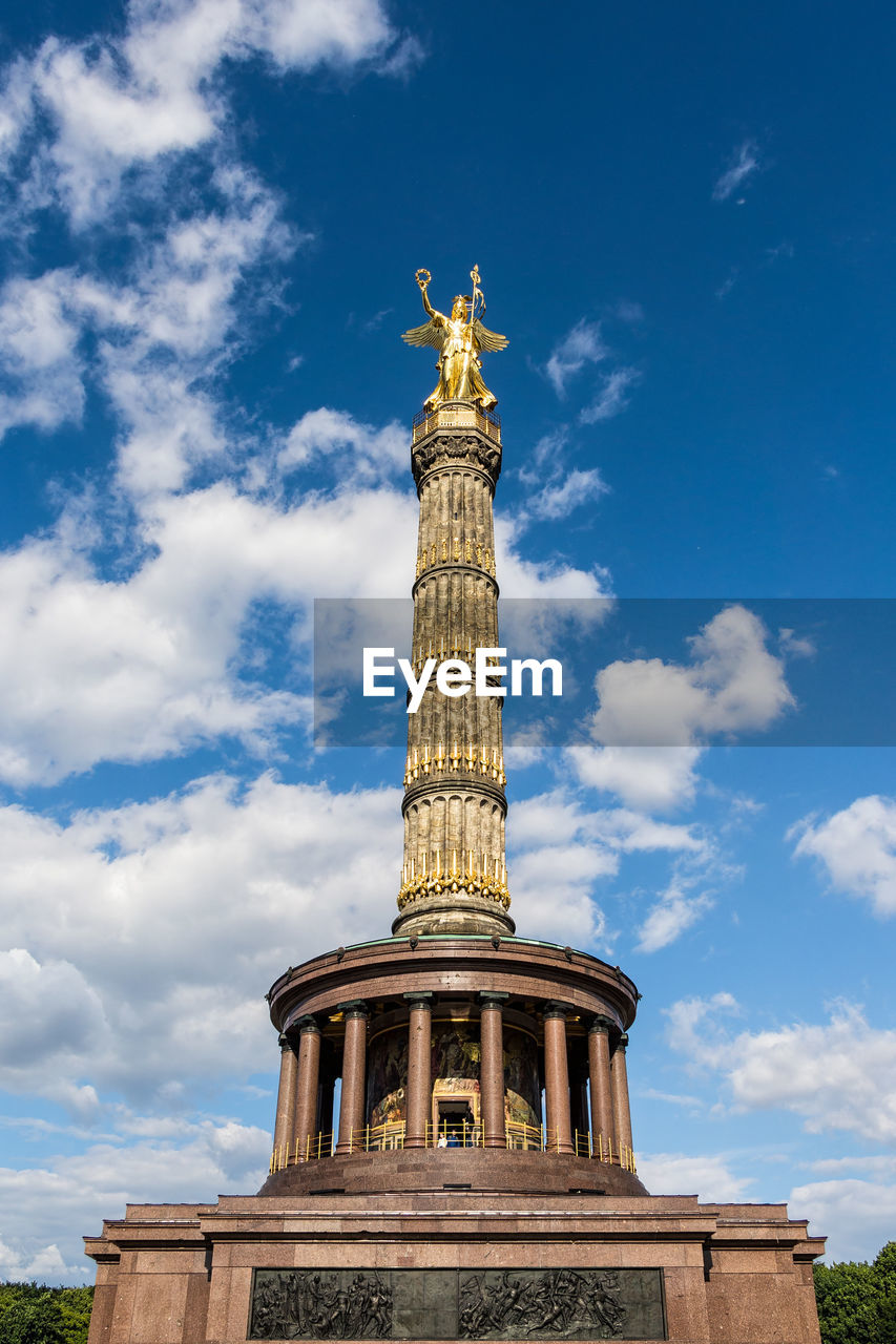 Low angle view of victory column against cloudy sky during sunny day