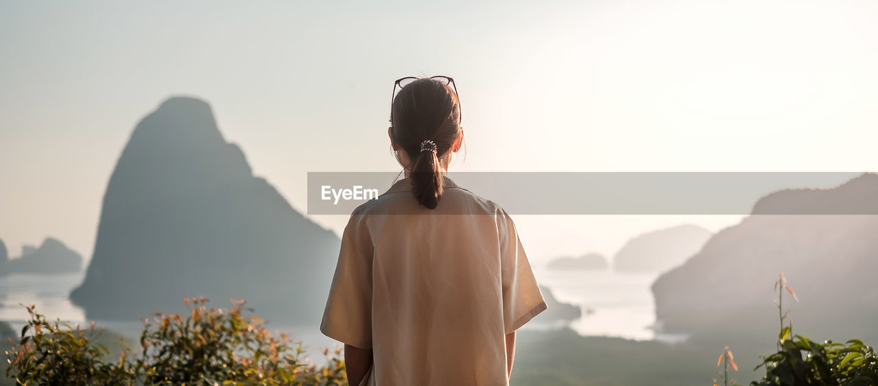 REAR VIEW OF WOMAN LOOKING AT MOUNTAIN