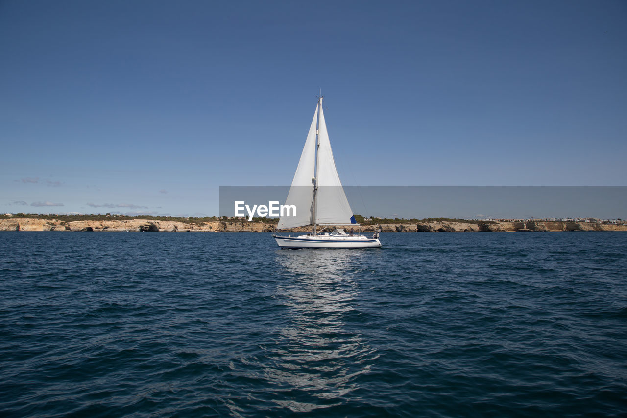 Sailboat sailing on sea against clear sky