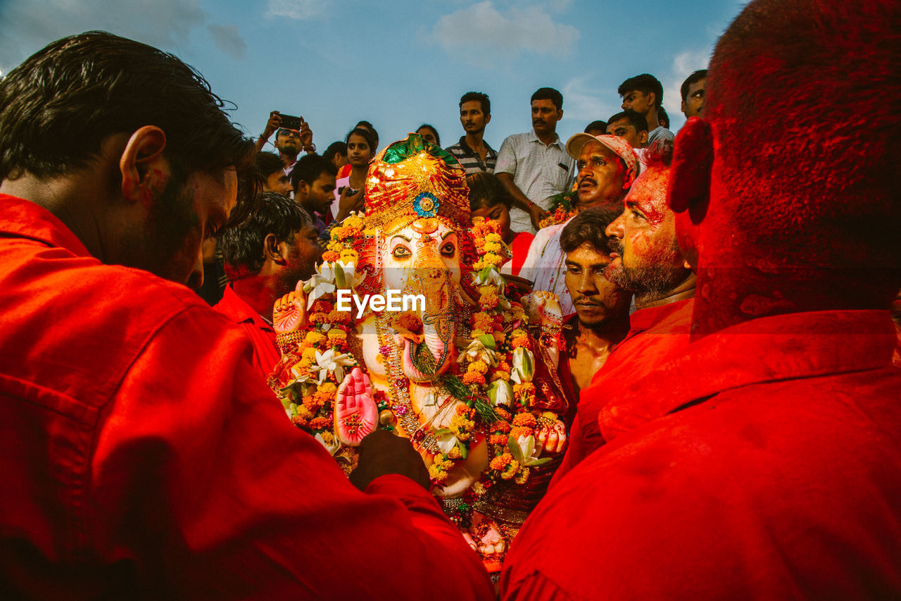 GROUP OF PEOPLE IN TRADITIONAL CLOTHING STANDING AGAINST THE SKY