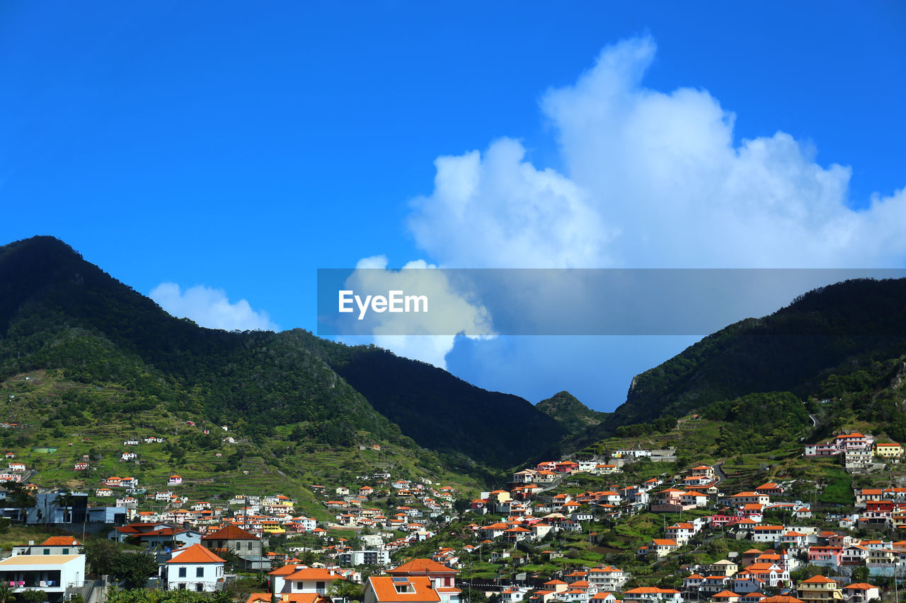 Panoramic view of townscape and mountains against blue sky