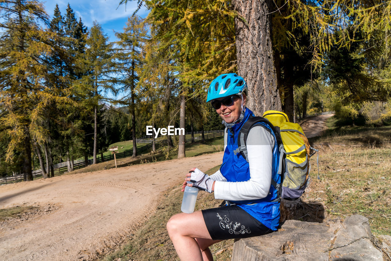 Smiling woman sitting on rock in forest