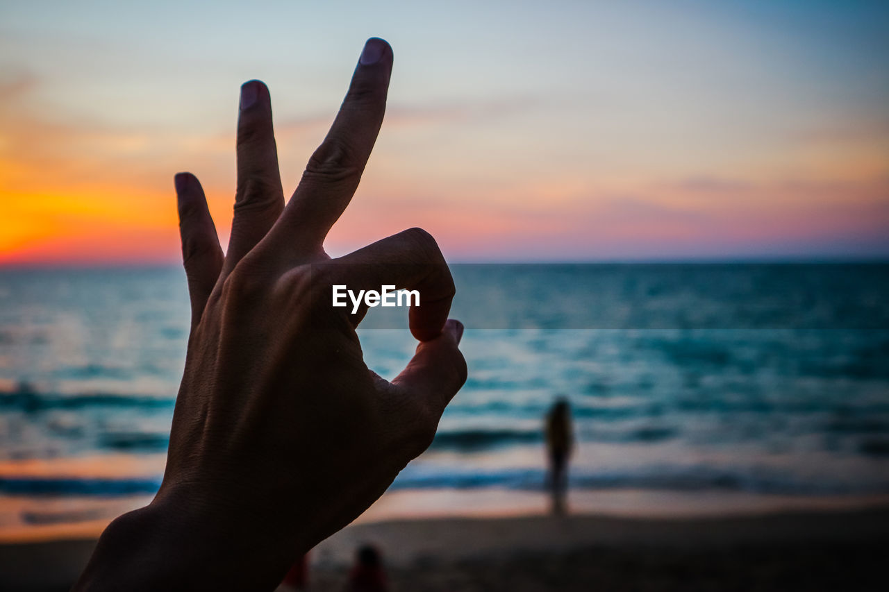 CLOSE-UP OF HAND ON SEA SHORE