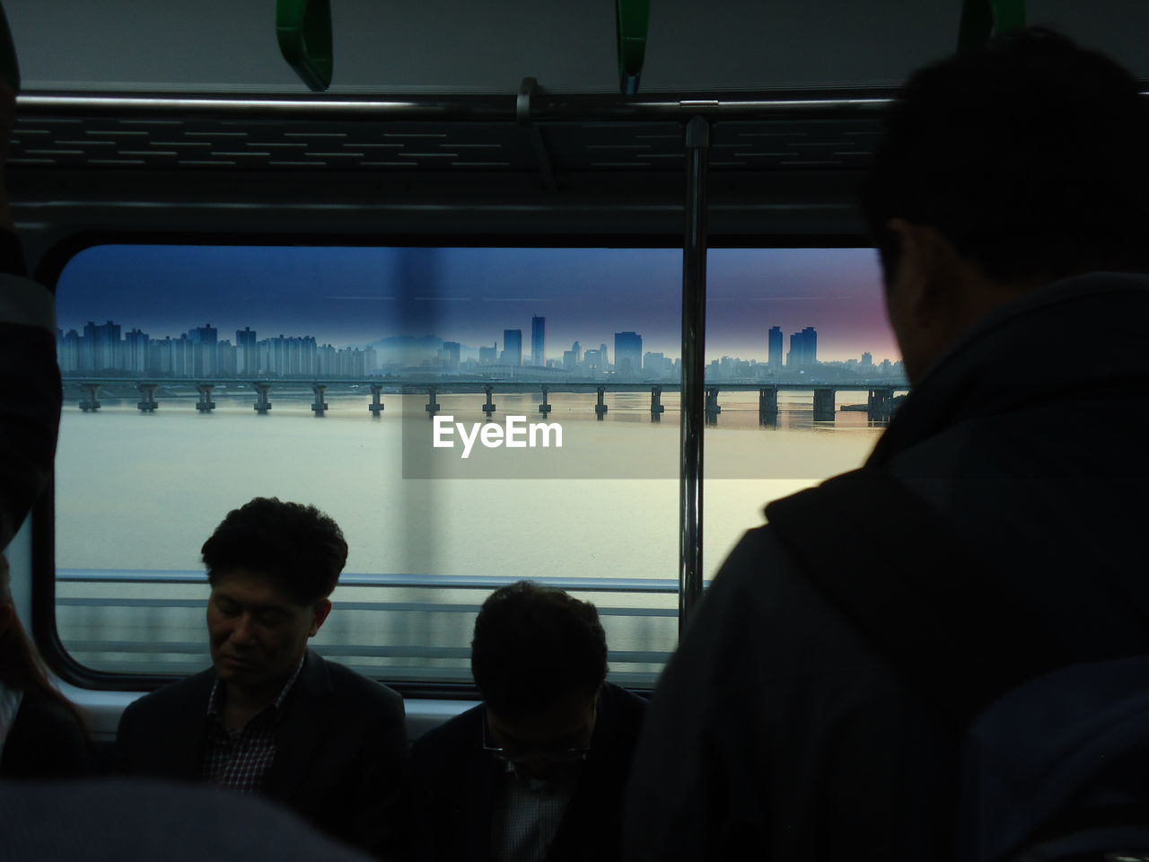 REAR VIEW OF MAN SITTING ON TRAIN AT RAILROAD STATION