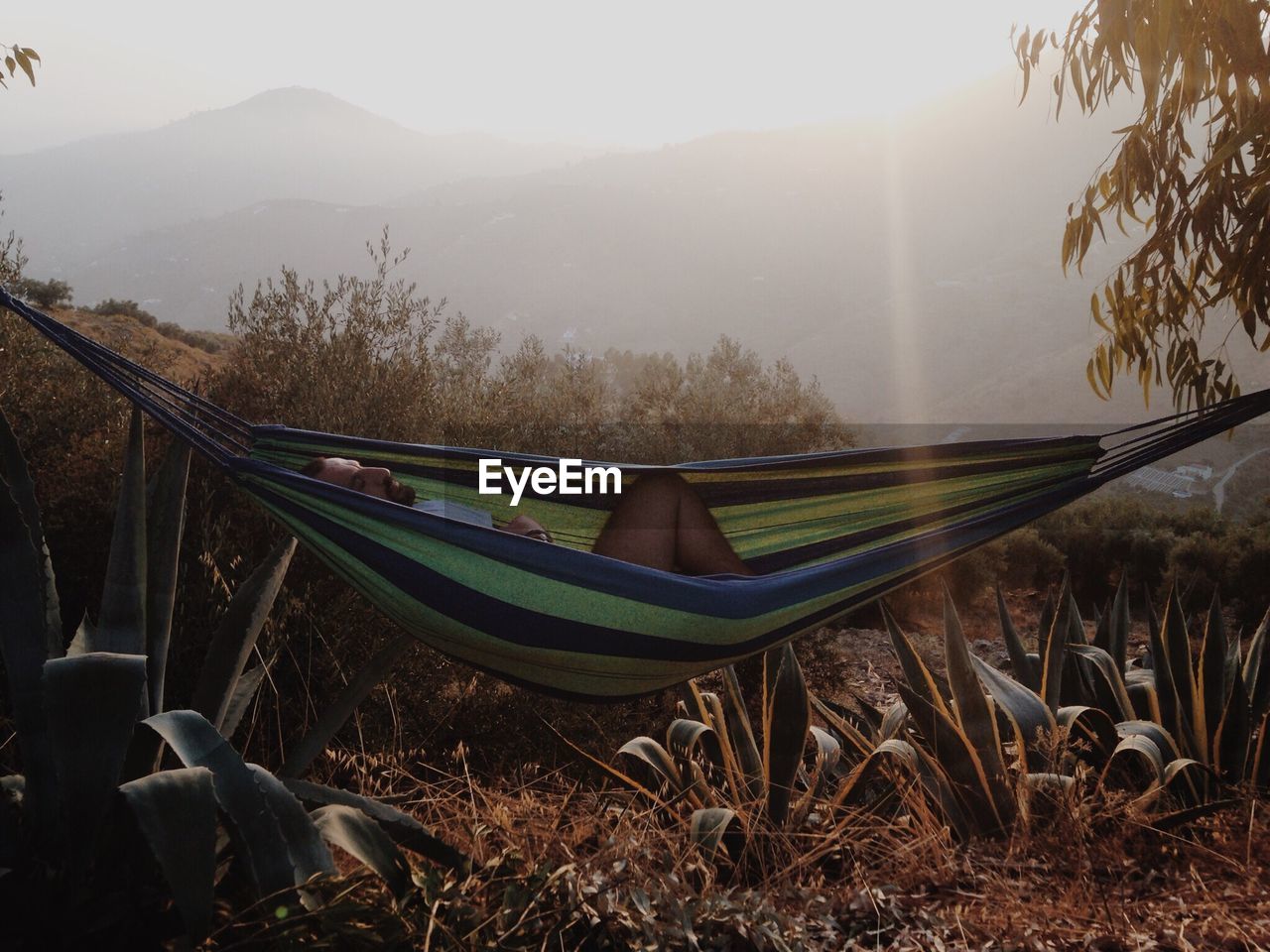 Man sleeping in hammock during sunset