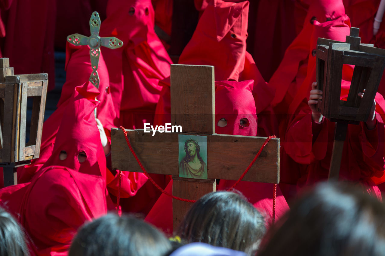 High angle view of penitentes holding cross while standing on street