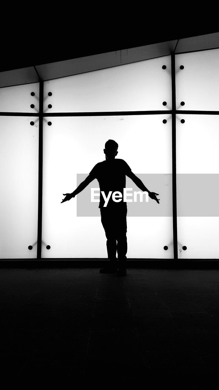 Rear view of silhouette man standing against wall