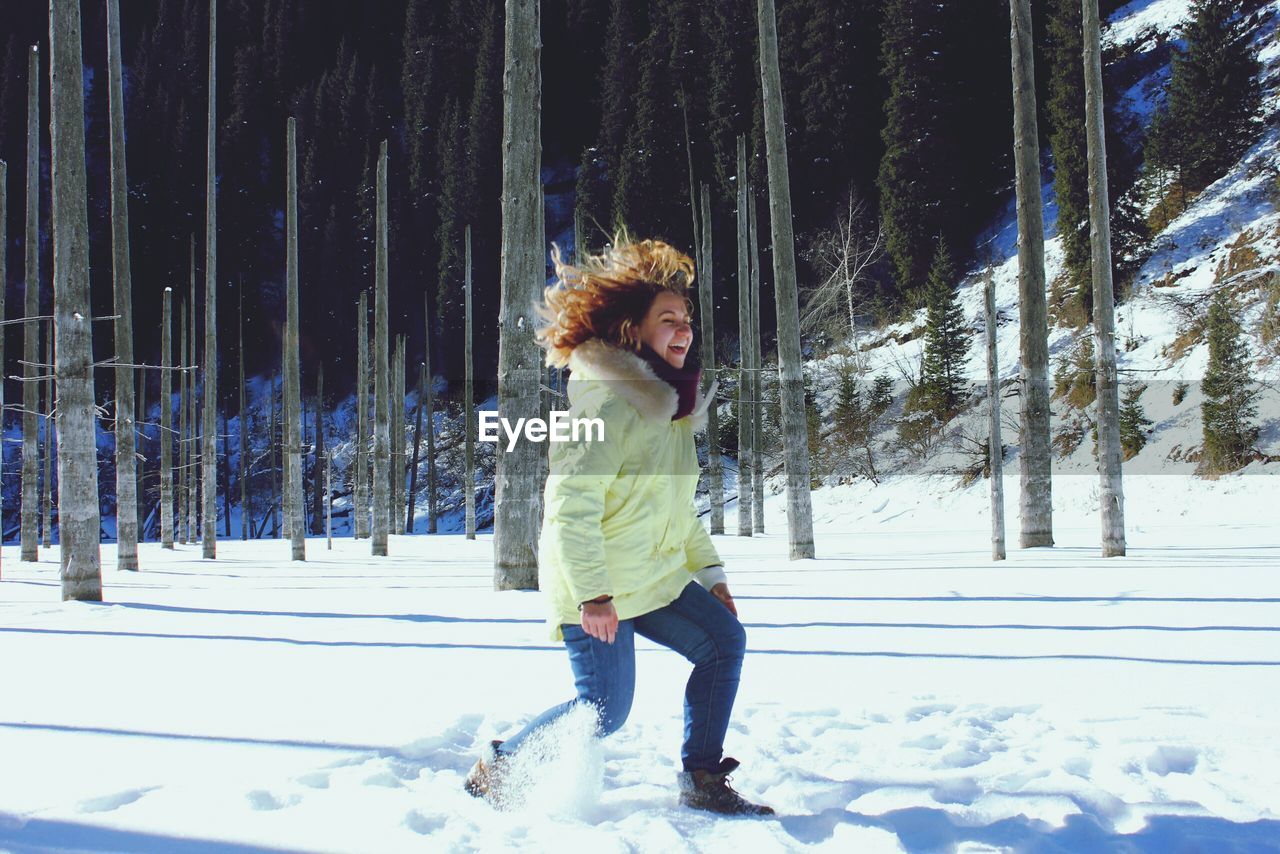 Happy woman playing with snow during winter