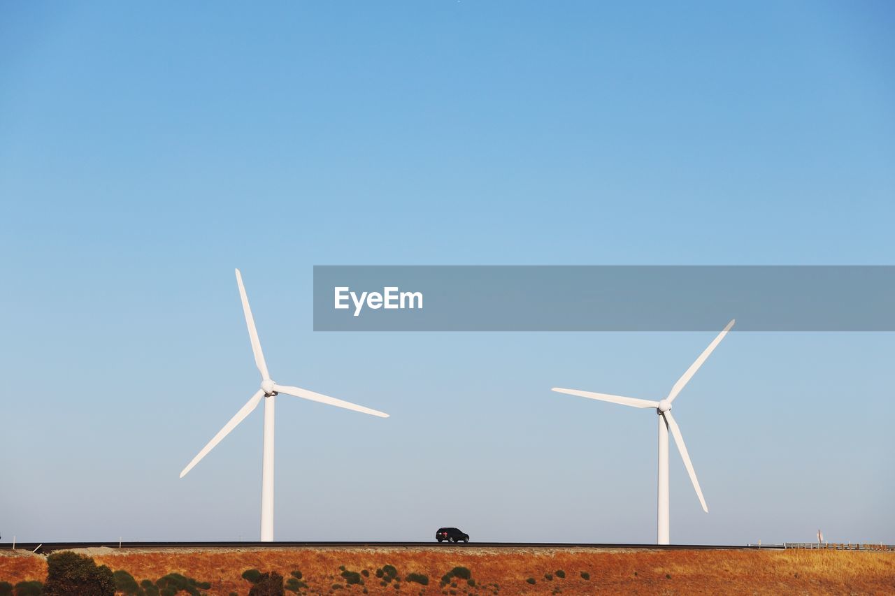 Wind turbines on field against clear sky