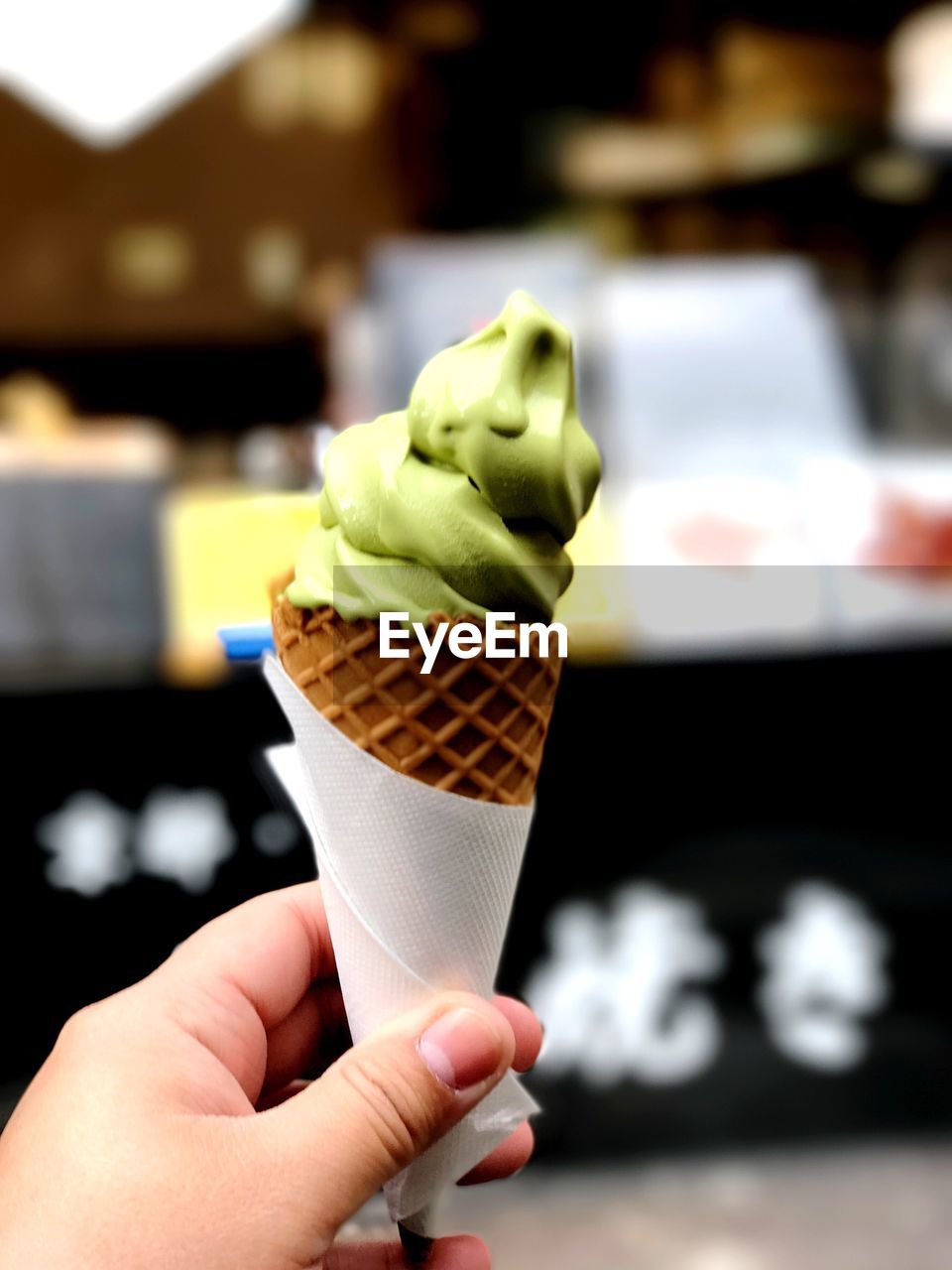 CLOSE-UP OF HAND HOLDING ICE CREAM CONE ON TRAY