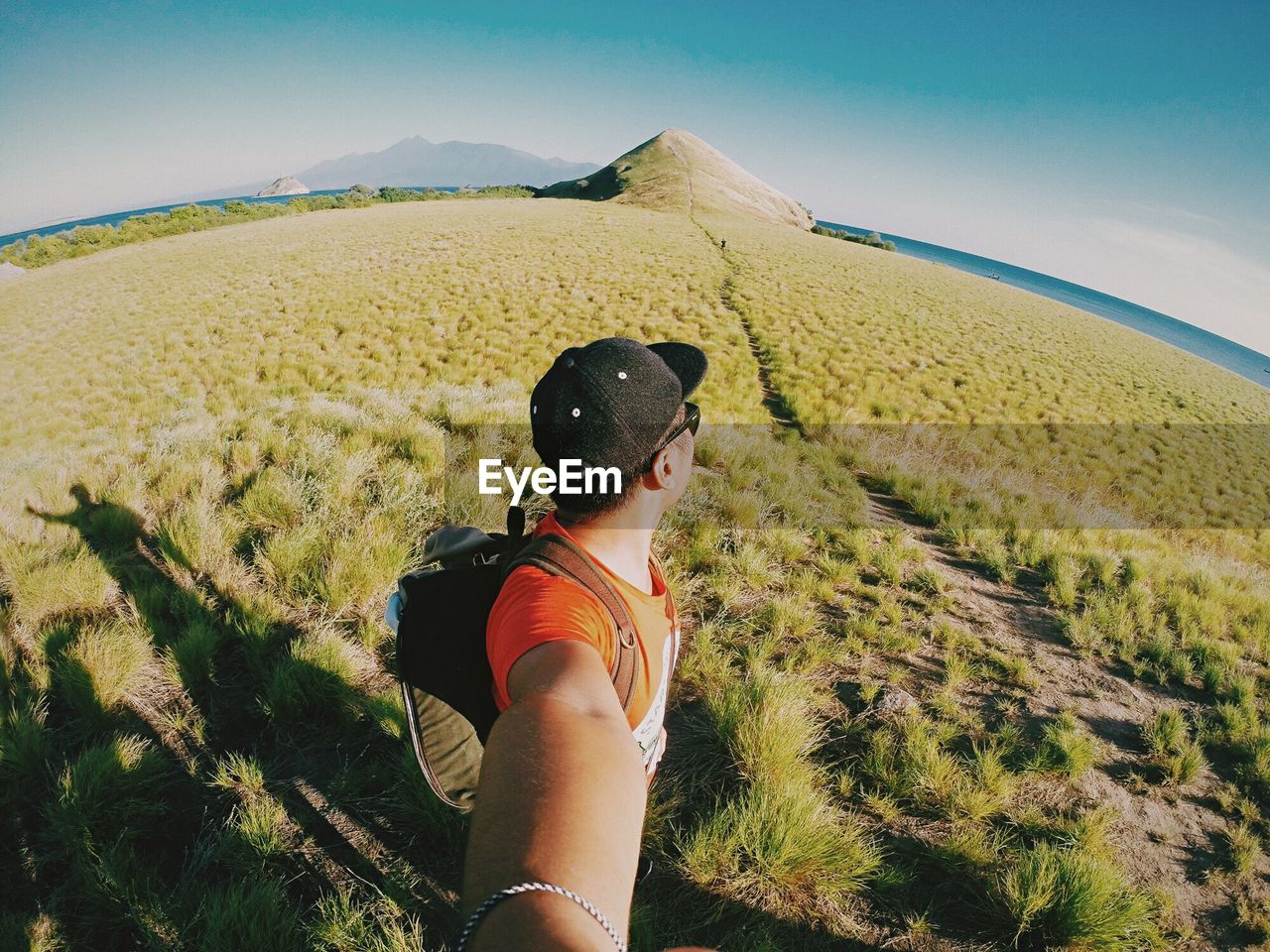 Man taking selfie while standing on grassy field against clear blue sky