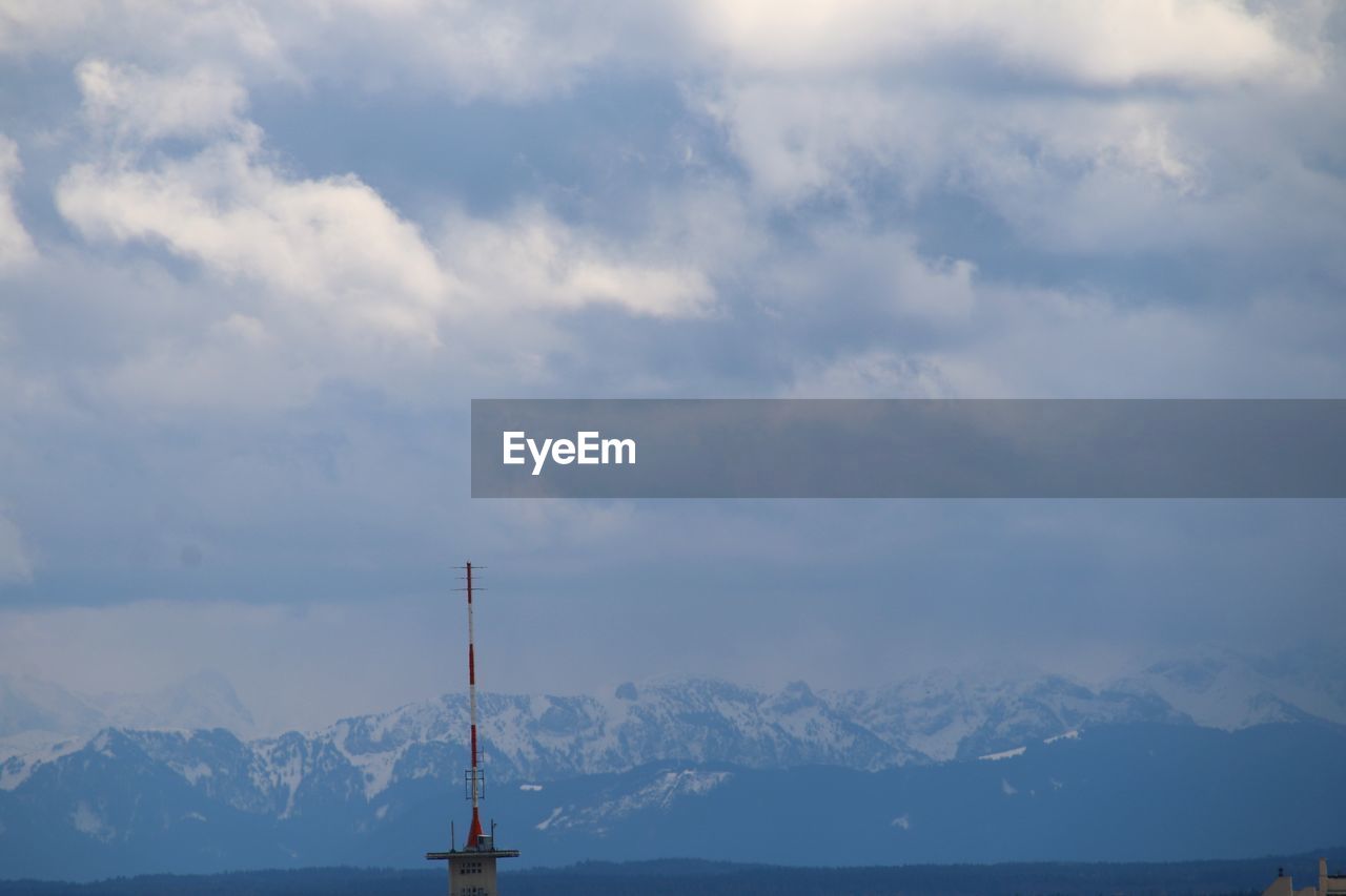 Communications tower and snowcapped mountains against sky
