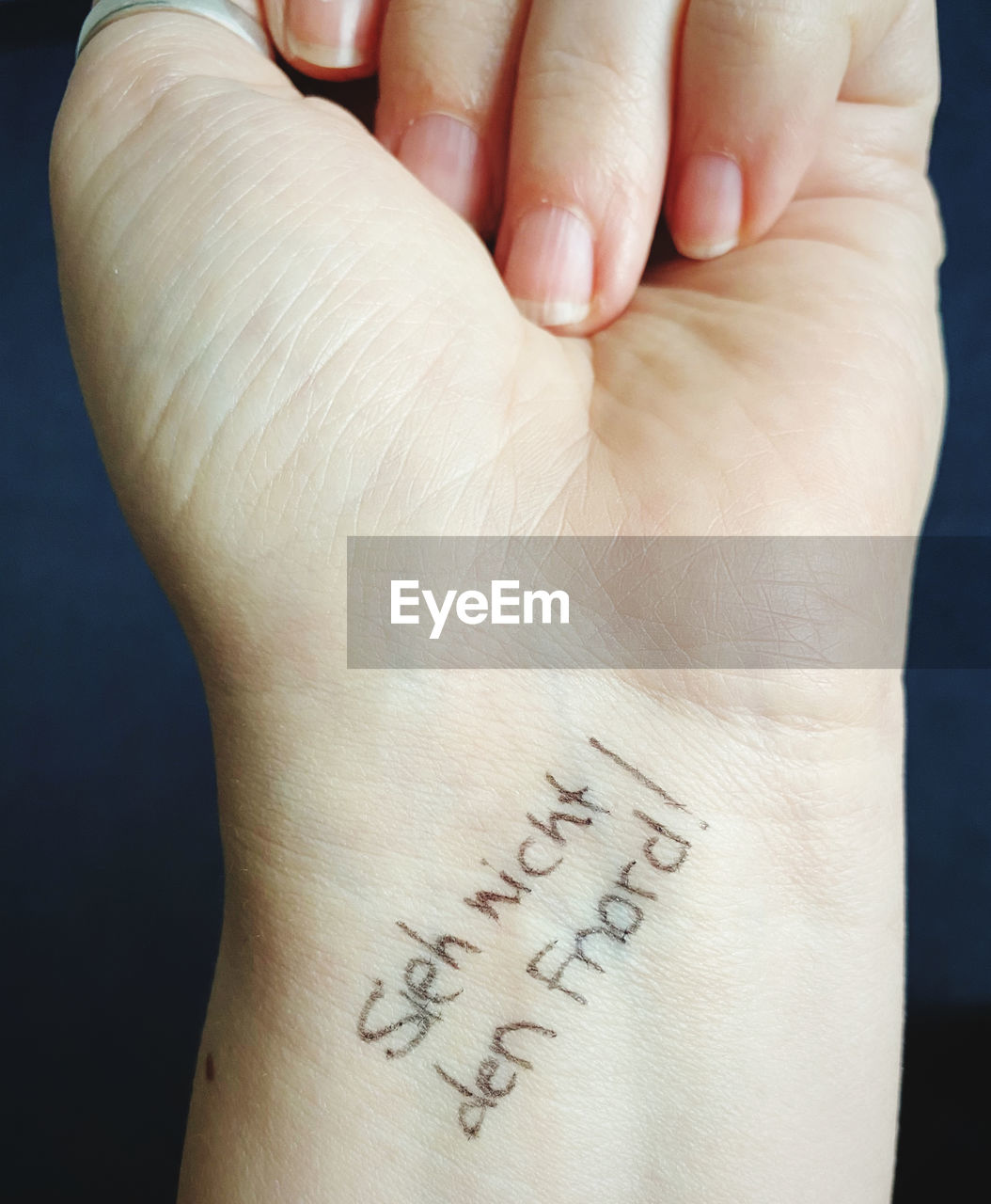 CLOSE-UP OF HAND WITH TEXT ON HUMAN FACE